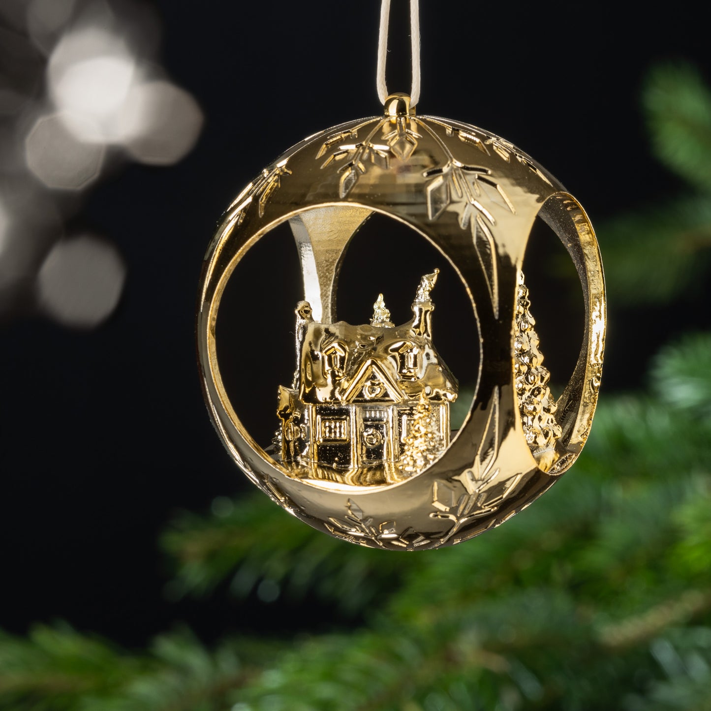 Auf dem Bild ist eine goldene Christbaumkugel zu sehen. Im Inneren der Kugel siehst du ein verschneites Haus im Wald, mit dem Weihnachtsmann im Schornstein und einem kleinen Schneemann in der Nähe. Diese charmante Szene verbreitet eine heimelige Atmosphäre und lädt zum Träumen ein.